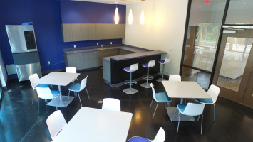 Blue and white walls with blue chairs and white tables in a work cafe.