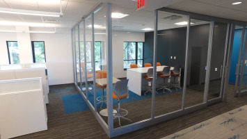 Glass panels create a square room with privacy from the remainder of an open workspace.