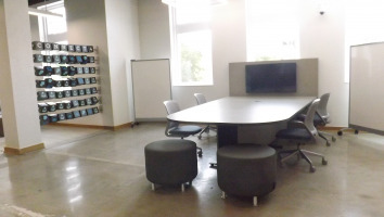 Stools with legs surround a table with a tv monitor for collaborative work.