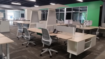 Group desking area with mesh back office chairs and a decorative high hanging shelf