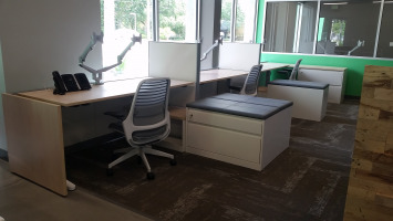 Open cubicle desk spaces with freestanding storage and filing cabinets. Chairs are mesh backed.