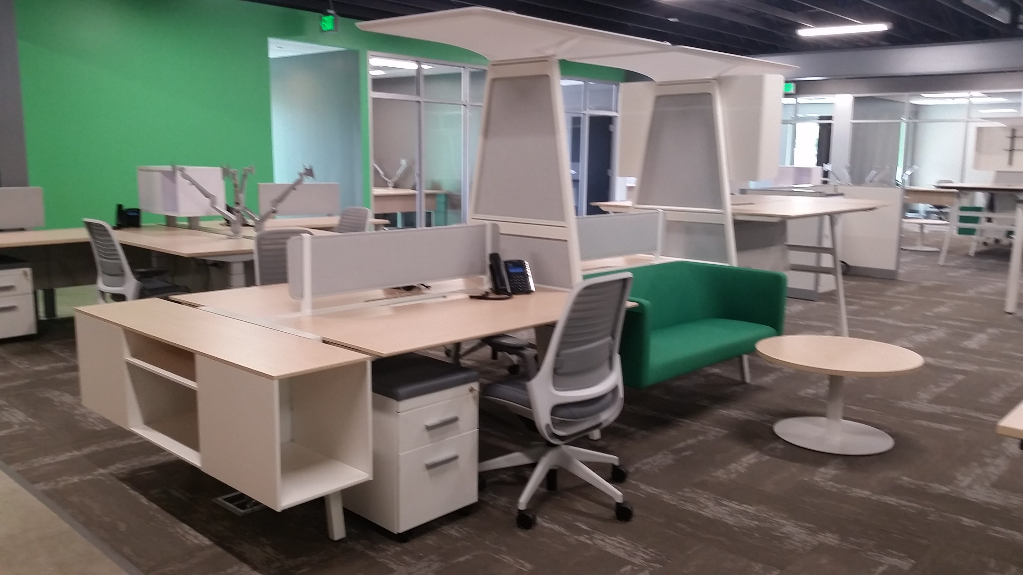 Group desking areas that have tall Turnstone Bivi standing unit. Green colored lobby furniture with blonde colored laminate for hotel desking.