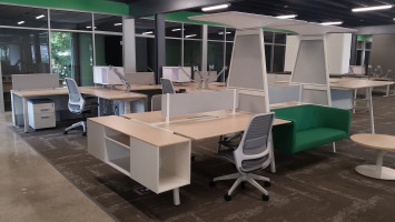 Group desking area with mesh back office chairs and a decorative high hanging shelf