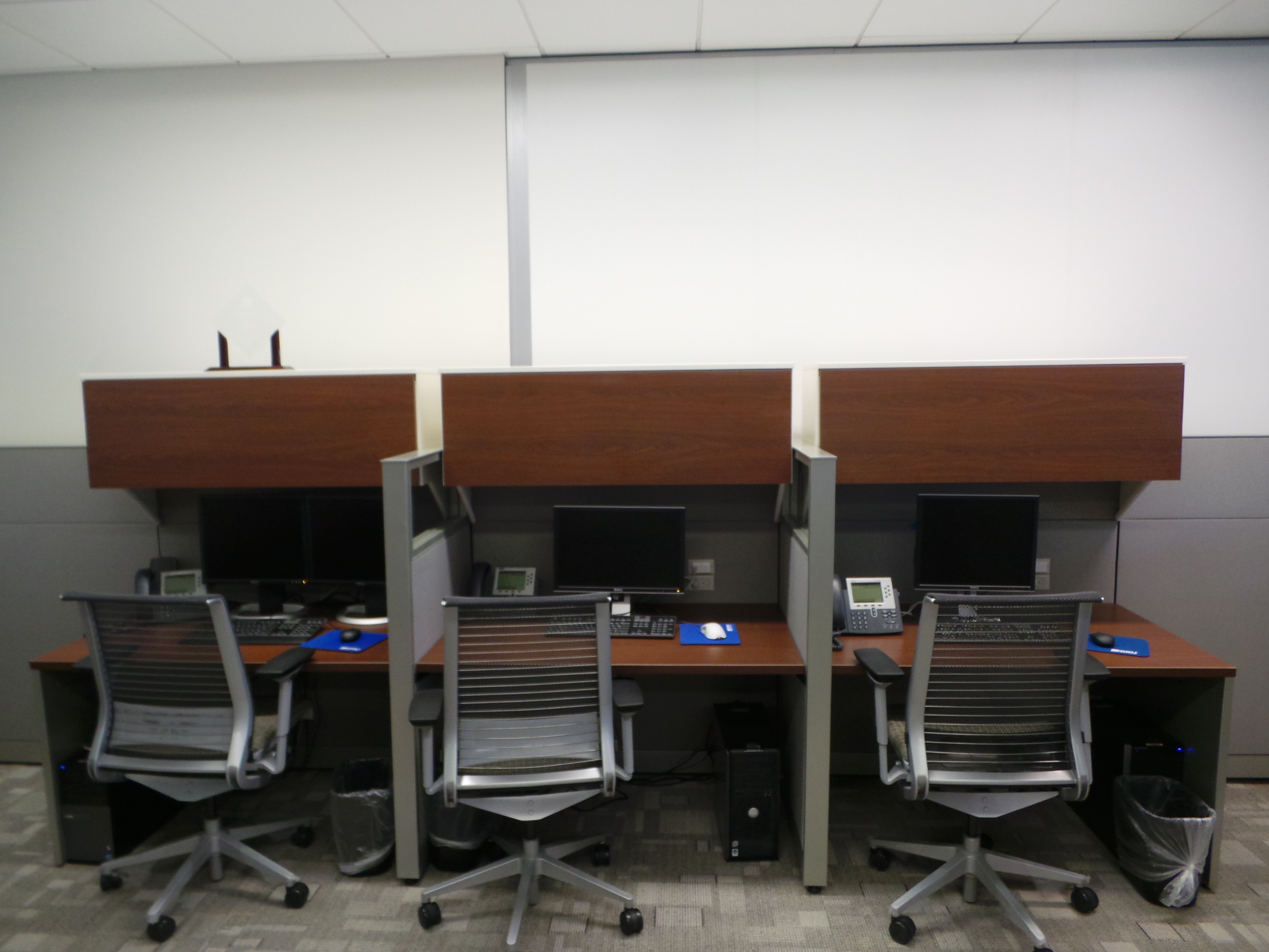 Black Steelcase Think chairs with cherry colored laminate call center desking with cubicle partitions.