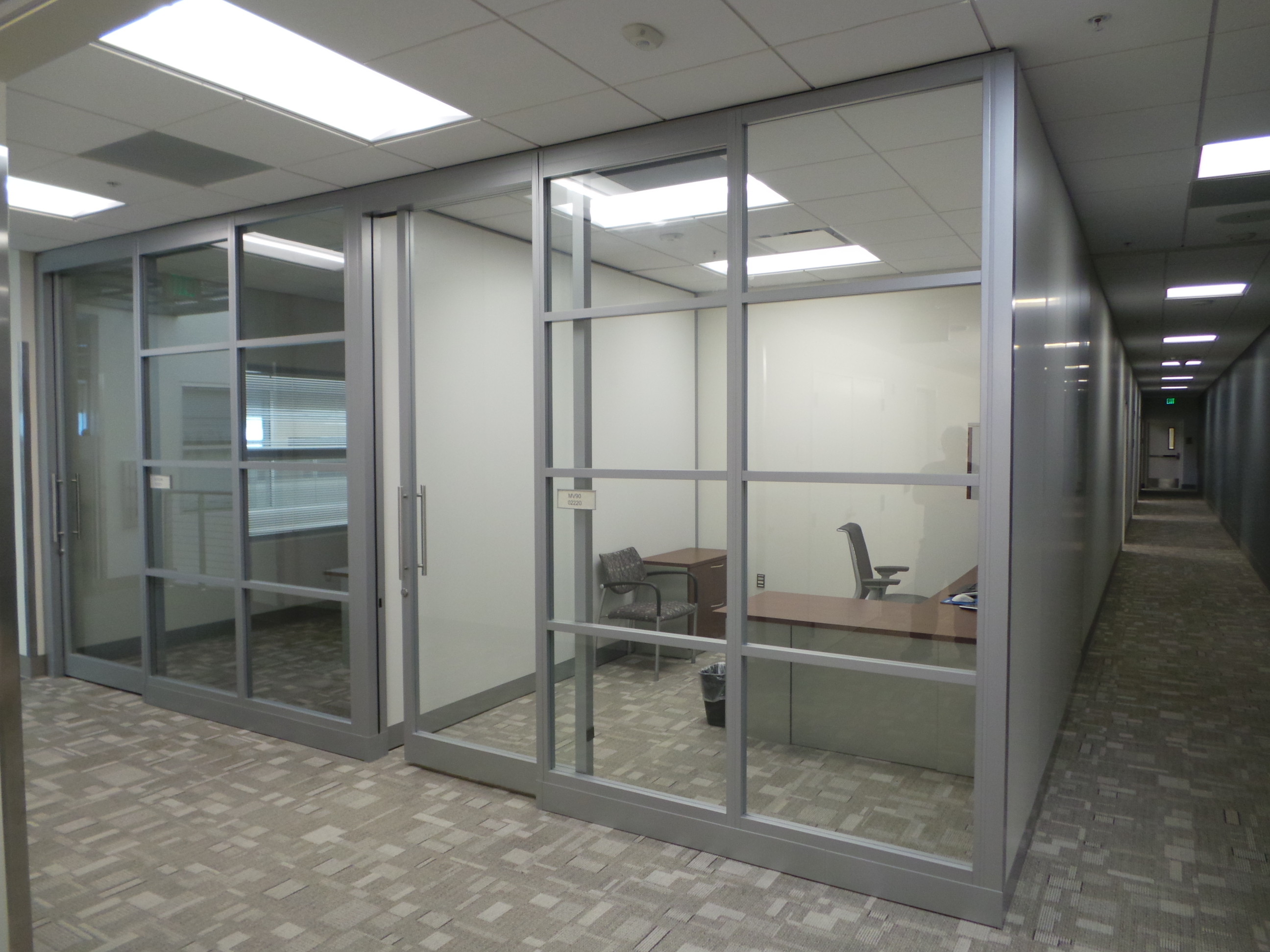 Privacy walls creating separated office space with a guest chair, a task chair, a desk and a storage cabinet.