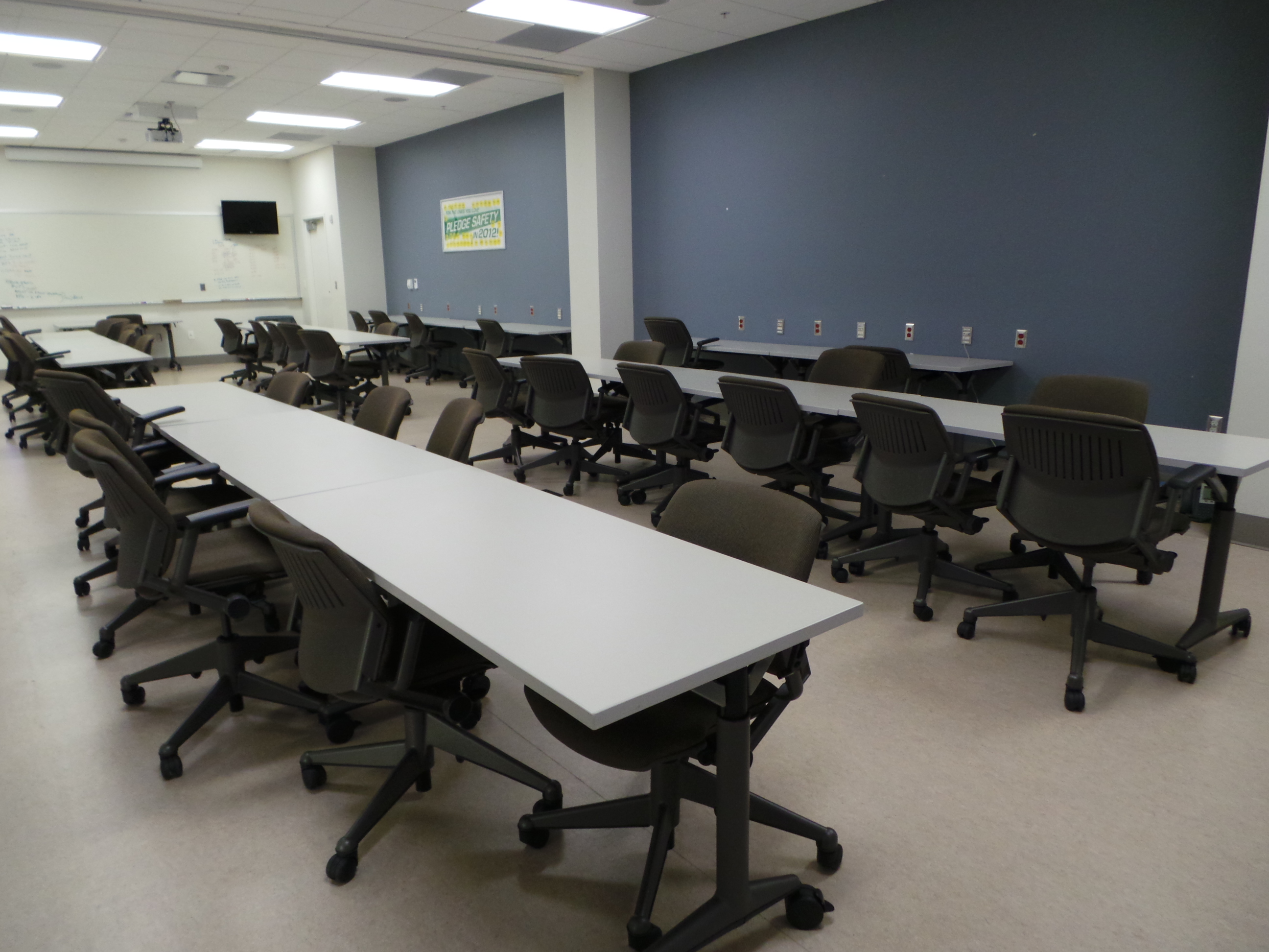 Conference room seating with white flip-top tables and black task seating throughout the entire room