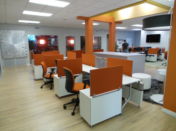 Hotel desking with orange chairs and orange privacy screens with white ottomans in a central lobby location
