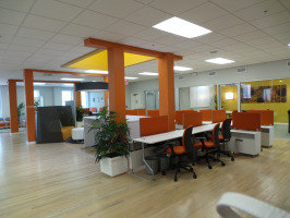 Hotel desking with red privacy screens and red chairs in a room with six orange colored floor to wall posts.