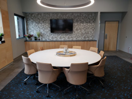 White roundtable meeting space with beige conference chairs. Room designed with geometric designs and brown and black colors.