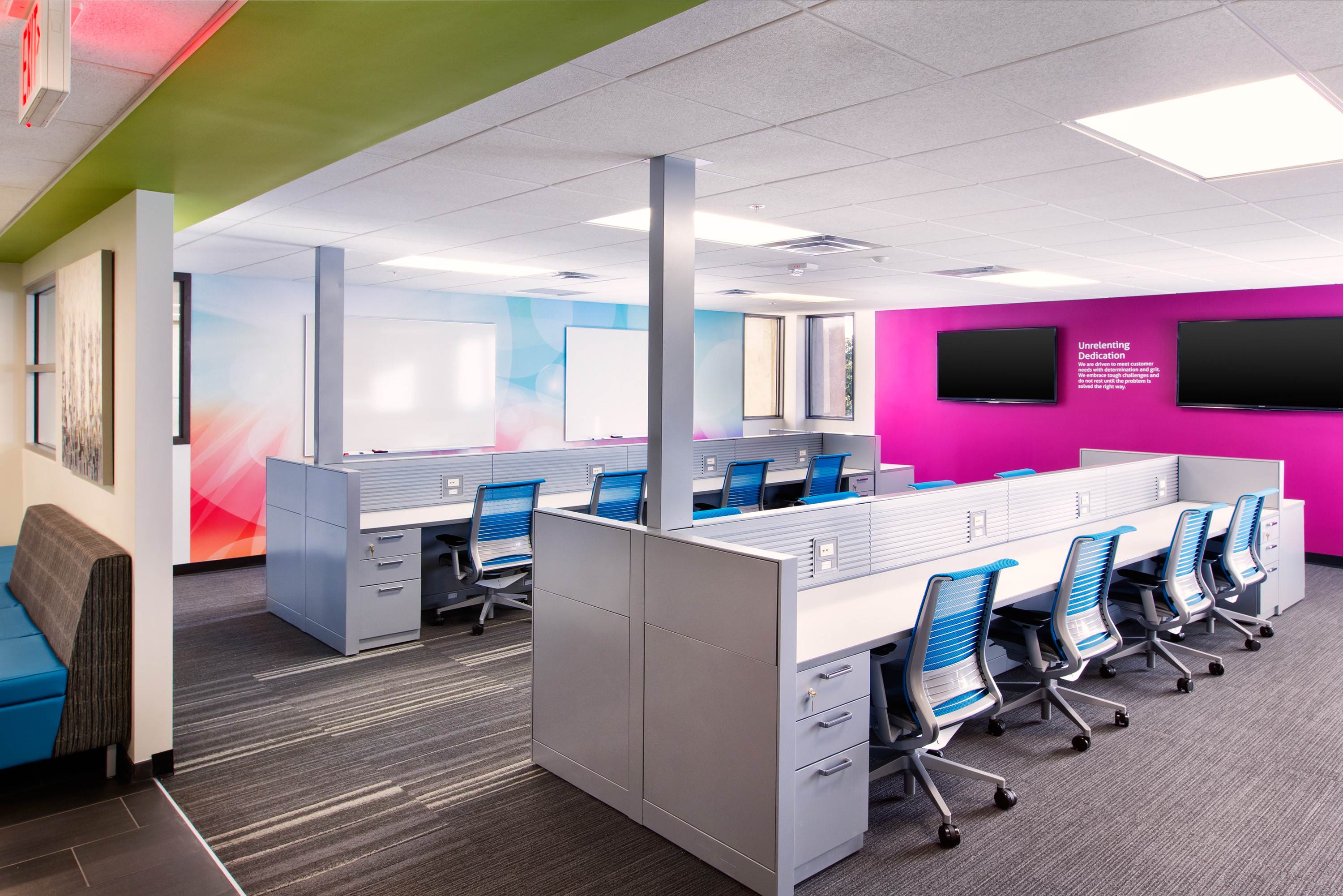 Bold pink accent wall with blue Steelcase Think chairs and white hotel desking with storage pedestals