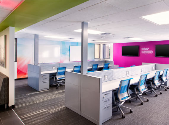 Bold pink accent wall with blue Steelcase Think chairs and white hotel desking with storage pedestals
