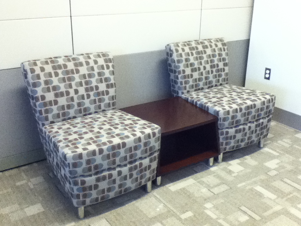 Multicolored lounge seating with end table between two chairs.