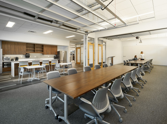 Large room with two long desks for meetings, as well as a counter island with seating in a work cafe corner