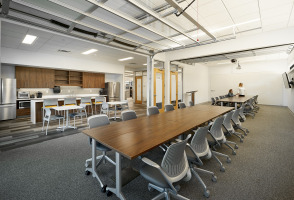 Large room with two long desks for meetings, as well as a counter island with seating in a work cafe corner