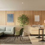 Expansive office space with a sitting area that has a couch and a height adjustable desk off to the side and a tree to enhance the user experience of the office space